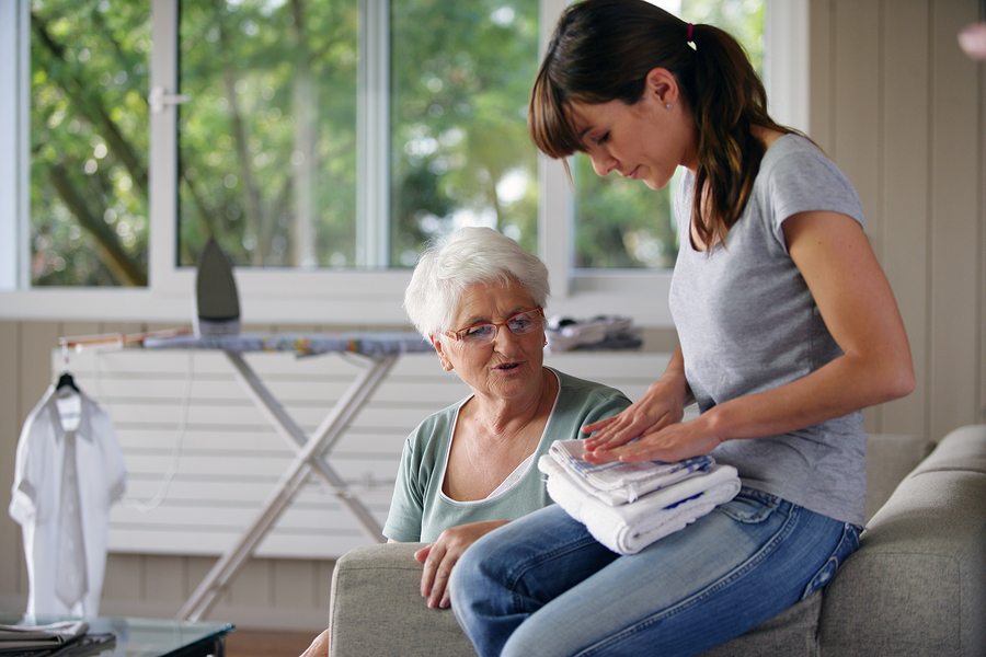 a home health aide folding an elderly woman's laundry