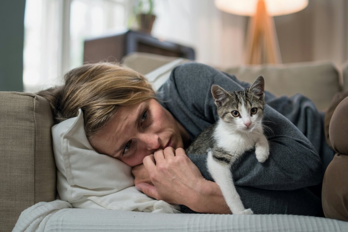 depressed woman snuggling with her cat on the couch