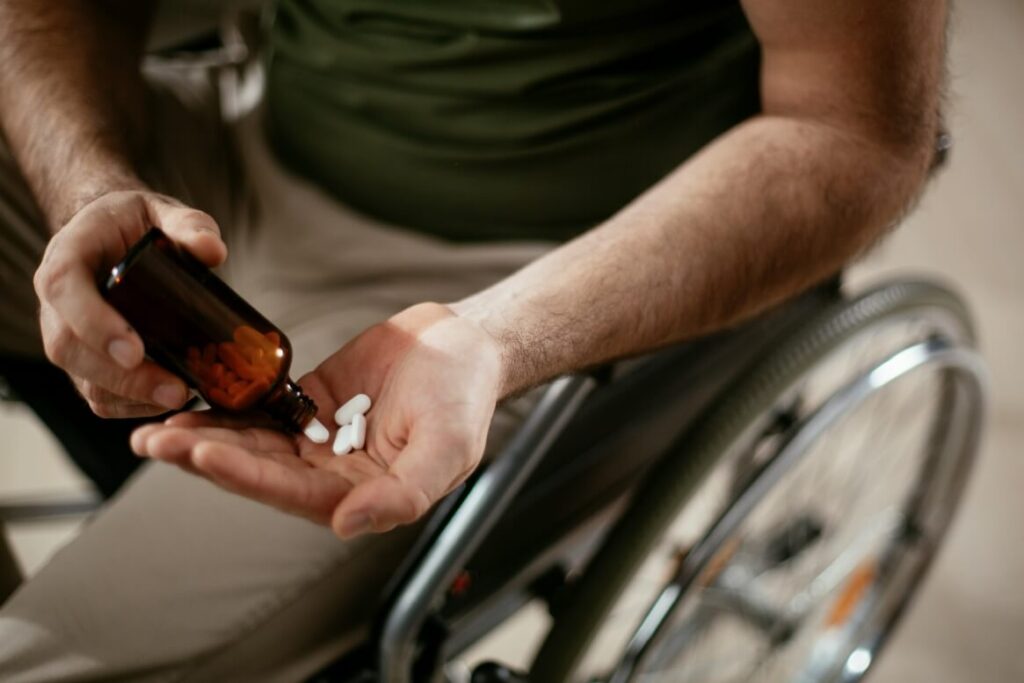 main in a wheelchair taking out medicines out of a bottle