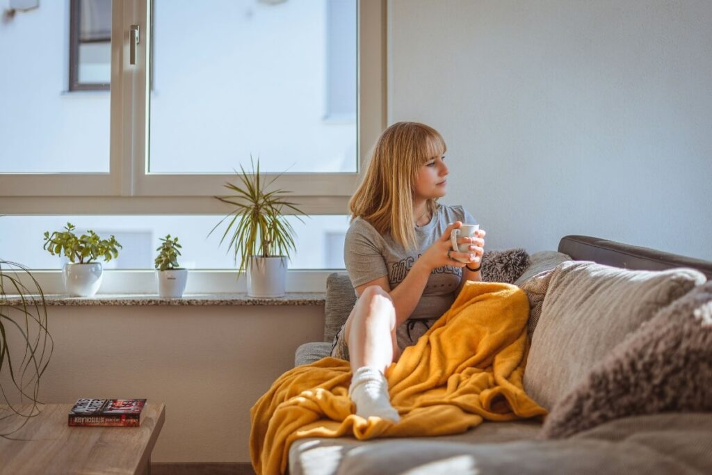 woman sitting on the couch holding a cup of coffee