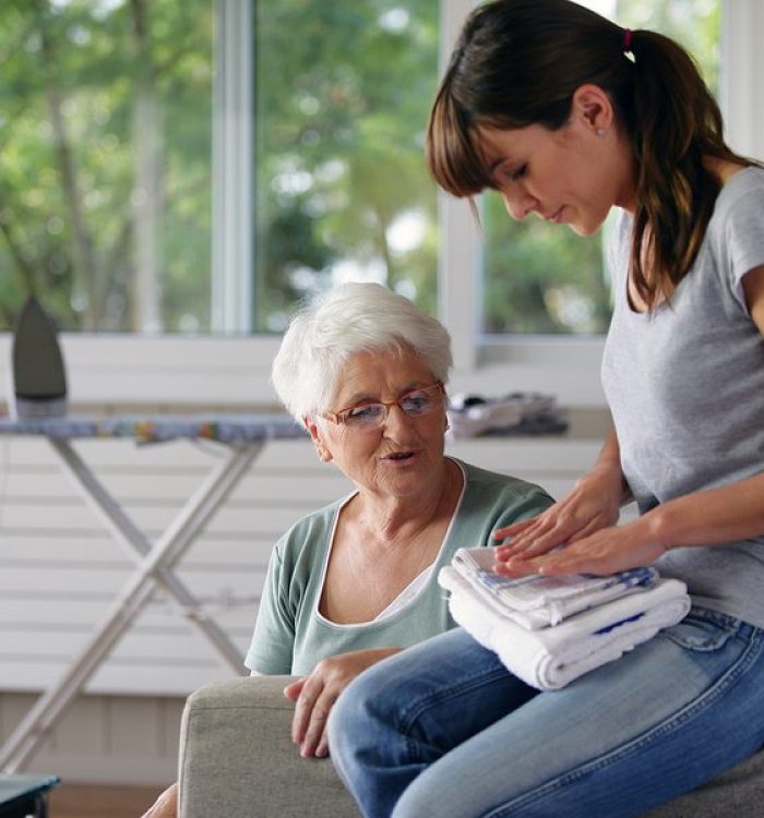 a home health aide folding an elderly woman's laundry