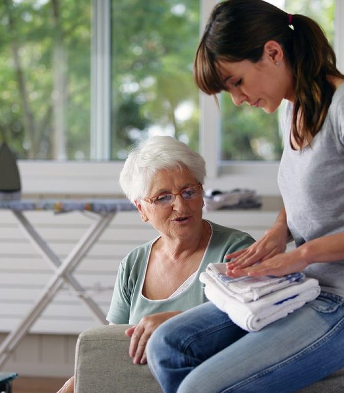 a home health aide folding an elderly woman's laundry