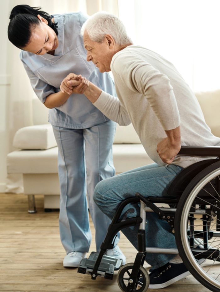 private nurse helping an elderly man stand up from the wheelchair